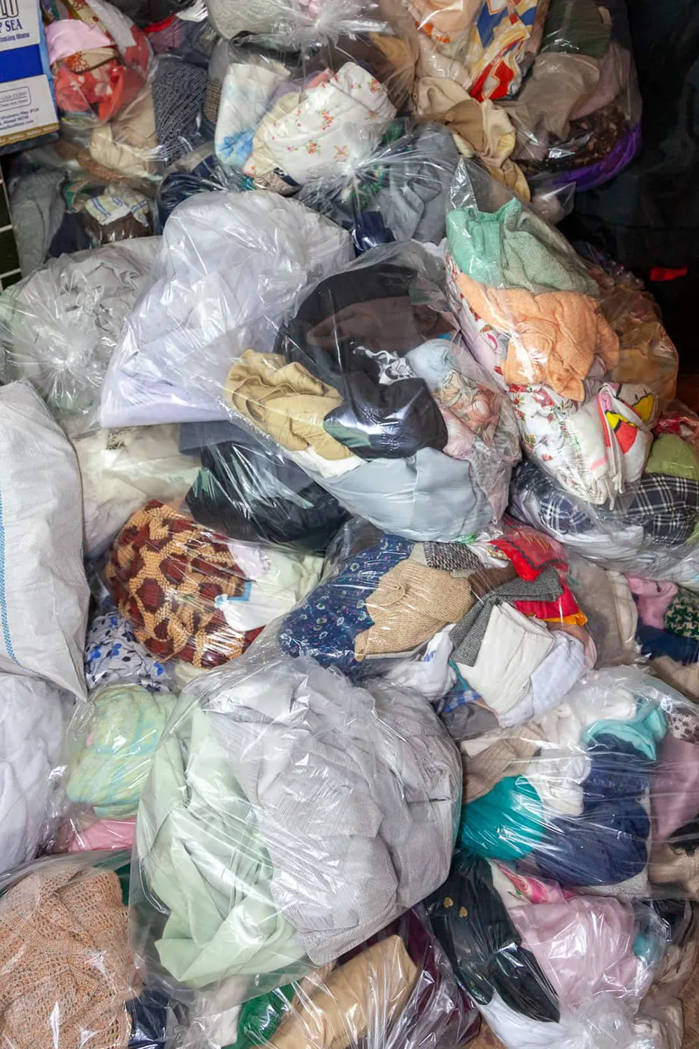 洋服がビニール袋に入って積み上げられている